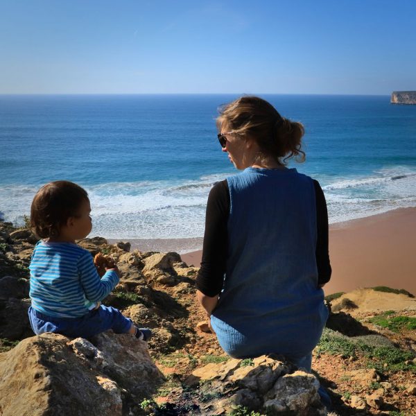Mother and son sitting on a cliff with a wonderfull view of Praia do Beliche, Sagres Portugal